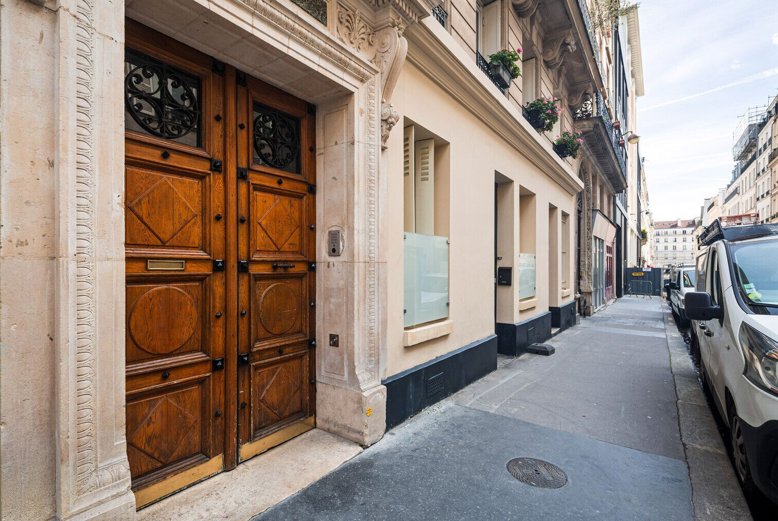 A narrow street with a row of buildings featuring large wooden doors and windows.