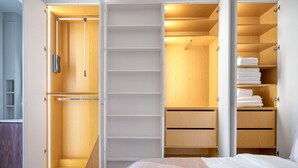 A bedroom with a bed, a wooden wardrobe with multiple shelves, and a built-in closet with hanging space. - Blueground | Batignolles, near park & restaurants (Paris)