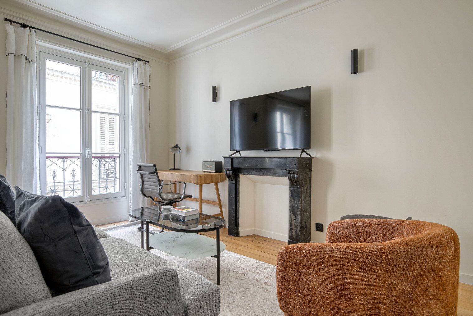 A living room with a sofa, a chair, a table with a lamp, a TV, and a fireplace.