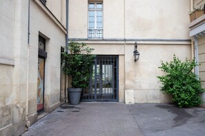 Stroll through the charming entrance, featuring a black gate and a large potted plant.