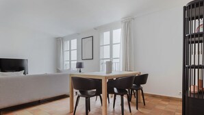 Et hotelværelse med en seng, et skrivebord med to stole, et fjernsyn og et vindue med gardiner.