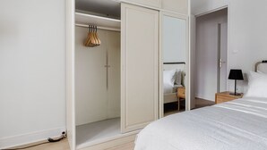 Et soveværelse med seng, natbord, skab og spejl.