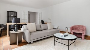 En moderne stue med en grå sofa, et rundt sofabord og en pink lænestol.