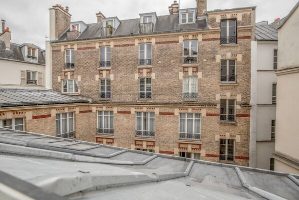 A multi-story building with brick facades, multiple balconies, and a flat roof. - Blueground | Le Marais - Republique, nr food (Paris)