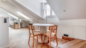 Un appartement moderne de style « loft », doté d’une verrière, d’une table de salle à manger ronde et de chaises en bois.