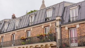 A row of brick buildings with dormer windows and a bell tower. - Blueground | Lamarck - Caulaincourt, nr dining (Paris)