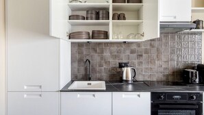 Eine moderne Küche mit weißen Schränken, einer schwarzen Arbeitsplatte, einem Edelstahlkocher und einem digitalen Backofen.