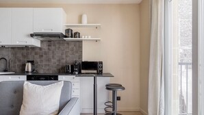 Eine moderne Küche mit grauem Sofa, einer Kaffeemaschine, einem Toaster und einem Wasserkocher.