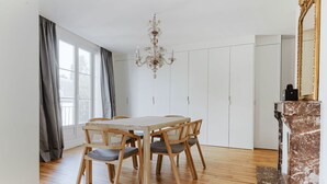 Un comedor con una mesa y sillas de madera, una araña y una chimenea de mármol.