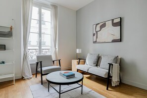 A modern living room with a sofa, armchairs, a coffee table, and a bookshelf.