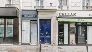 Katunäkymä, jossa näkyy suljettu liike nimeltä ’REPASSAGE’ ja toinen liike nimeltä ’CELLAR’, jonka yläpuolella on vihreä markiisi.