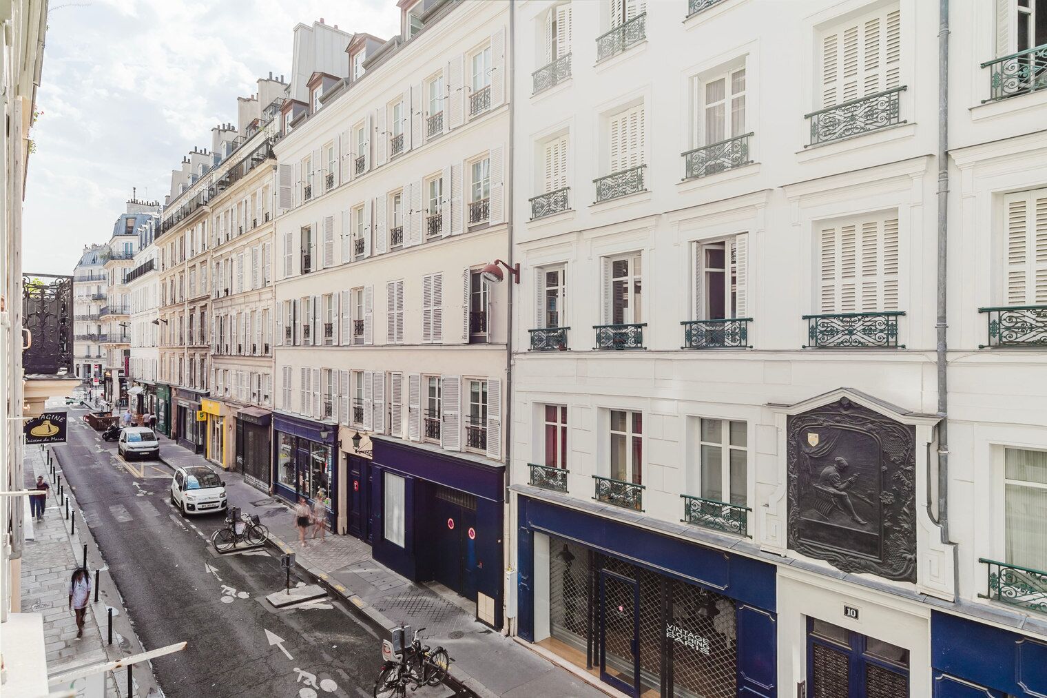 A multi-story building with white facades, balconies, and a street view.