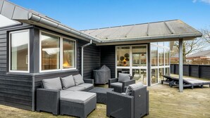 A covered outdoor seating area with wicker furniture and a glass door leading to an interior space.