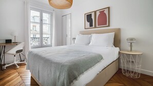 A bedroom with a bed, a desk, and a chair.