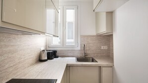 A modern kitchen with a window, stainless steel appliances, and light-colored cabinetry.