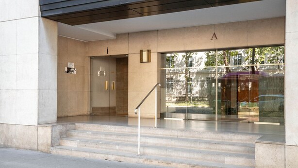A modern building entrance with a glass door, a staircase, and a sign with the letter 'A'. - Blueground | Champ de Mars, furnished & equipped (Paris)