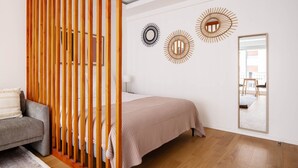 A modern bedroom with a bed, a grey sofa, wooden slats, and decorative wall mirrors. - Blueground | Champ de Mars, furnished & equipped (Paris)
