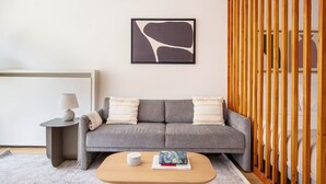 A modern living room with a grey sofa, a wooden coffee table, and a framed abstract painting on the wall. - Blueground | Champ de Mars, furnished & equipped (Paris)