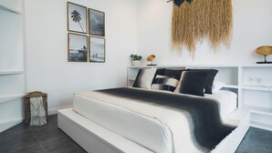 A modern bedroom with a large bed, a wall-mounted air conditioner, and a decorative wall hanging. - Angel Bay (Tabanan)