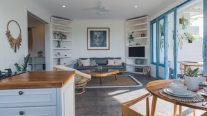 A modern living room with a grey sofa, wooden coffee table, and a dining area with a round table and chairs. - Angel Bay (Tabanan)