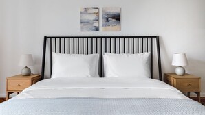 Une chambre à coucher comprenant un lit, deux tables de chevet et deux lampes fixées au mur.