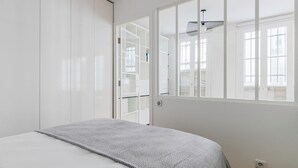 Une chambre à coucher avec un lit, une armoire, une fenêtre et un ventilateur de plafond.