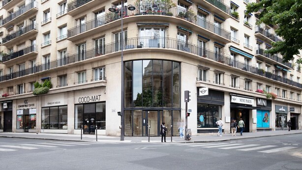 Un edificio de varios pisos con un hotel boutique en la planta baja llamado "COCO-MAT" y un "CONVERTIBLE CENTER" al otro lado de la calle.