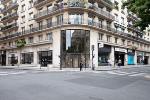 Un edificio de varios pisos con un hotel boutique en la planta baja llamado "COCO-MAT" y un "CONVERTIBLE CENTER" al otro lado de la calle.