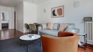 Una sala de estar moderna con un sofá gris, una mesa de centro redonda y un sillón naranja vibrante.