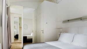Een hotelkamer met een groot bed, een kledingkast, een nachtkastje en een spiegel.