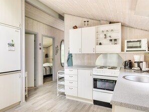 Een compacte keuken met witte kastjes, een magnetron, waterkoker en koffiezetapparaat.
