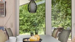 A dining table with plates, cups, and a basket of bread, set against a window with a view of greenery. - "Gorica" - 30km from the sea by Interhome (Toftlund)