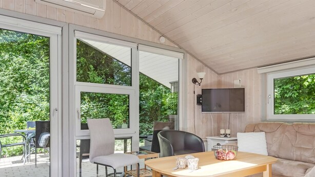 A modern room with a wooden ceiling, a flat-screen TV, a sofa, a dining table, and a sliding glass door leading to an outdoor area. - "Gorica" - 30km from the sea by Interhome (Toftlund)