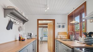 A compact kitchen with wooden countertops, a built-in oven, and a view into the dining area. - "Hakon" - 40m from the sea by Interhome (Nexø)