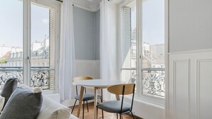 Ein Balkon mit weißem Tisch und Stühlen, einer Sitzecke und Blick auf Gebäude.