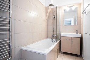 Et stilfuldt badeværelse med badekar, brusekabine i glas og et spejl med vask.