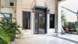 Una entrada de edificio con puertas dobles, un pequeño porche y plantas en macetas.