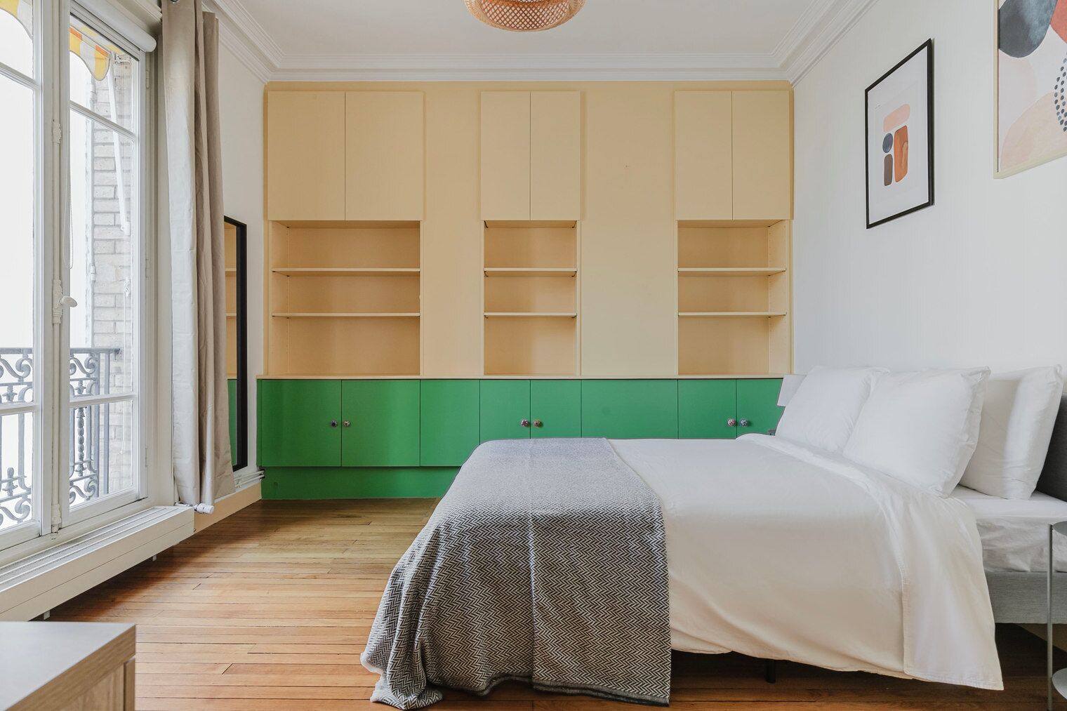 A bedroom with a bed, a green and beige wardrobe, a window with curtains, and a picture on the wall.