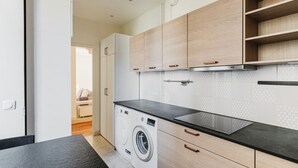 Una cocina moderna con lavadora, armarios de madera y encimera negra.