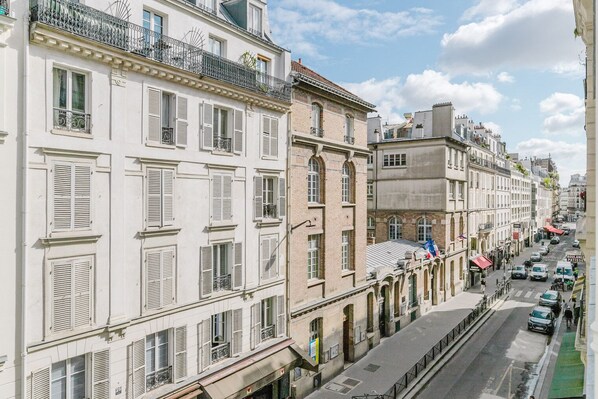 A row of multi-story buildings with white facades and shuttered windows, typical of a European cityscape.