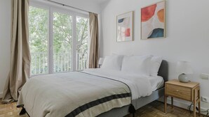 A bedroom with a bed, a nightstand, a lamp, and two abstract paintings on the wall. - Blueground | Pereire, elevator, near Porte Mailot (Paris)