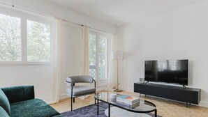 A modern living room with a sofa, a chair, a TV, and a coffee table. - Blueground | Pereire, elevator, near Porte Mailot (Paris)
