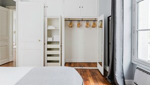 A bedroom with a bed, a walk-in closet with hanging space, and a window with curtains.