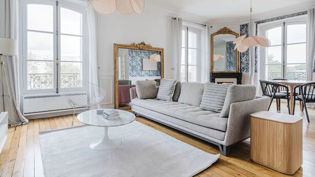 A modern living room with a sofa, a coffee table, and a dining area with chairs.