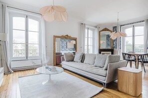 Een moderne woonkamer met een bank, een salontafel en een eetgedeelte met stoelen.
