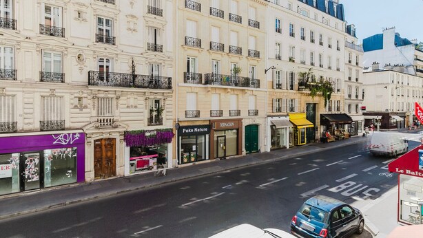 A street view with a row of buildings, including a shop named 'Poke Nature'. - Blueground | Invalides, nr embassies & museum (Paris)