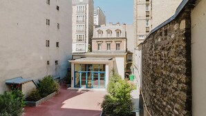 A narrow urban street with a building featuring a blue entrance and a red-tiled roof. - Blueground | Invalides, nr embassies & museum (Paris)