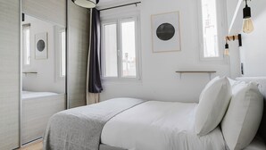 Ein modernes Schlafzimmer mit einem Bett, einem großen Spiegel und einem Fenster.