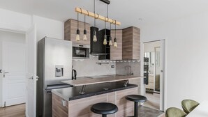 Eine moderne Küche mit integrierter Kochinsel, Edelstahlgeräten und einer Holzrückwand.