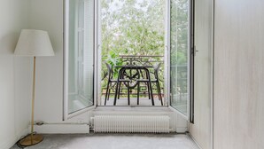 A room with a large window, a radiator, a floor lamp, and a table with chairs outside.